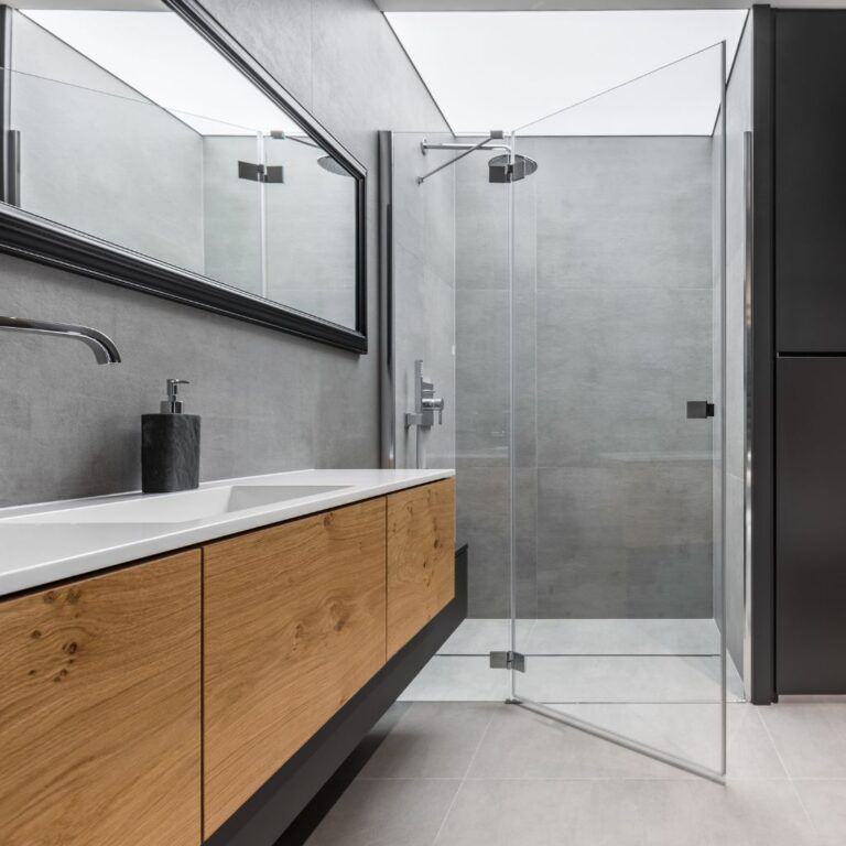 Baño en Illescas con plato de ducha del mismo material que el suelo y mampara de cristal transparente abatible