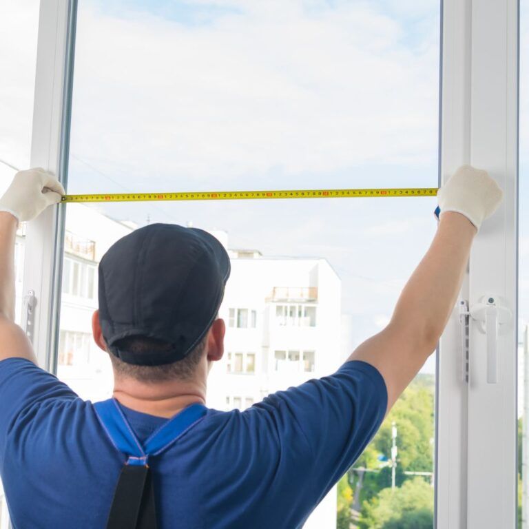 Operario midiendo una ventana de aluminio para colocar cristal durante la instalación en Illescas