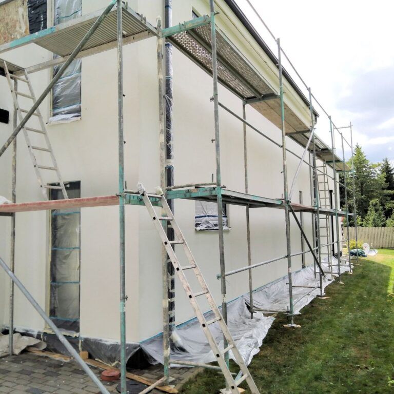 Pintores en Illescas aplicando pintura en la fachada de una casa con andamios